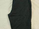 men ' s black pants laying on a bed with a white sheet