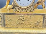 a gold clock with a statue of a woman and a dog