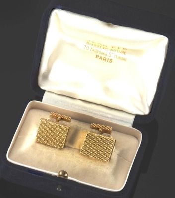 une paire de boutons de manchette plaqués or, présentés dans un coffret posé sur un fond noir