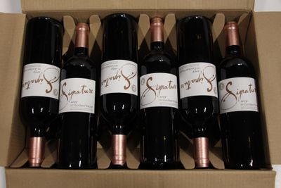 six bottles of wine in a cardboard box on a table