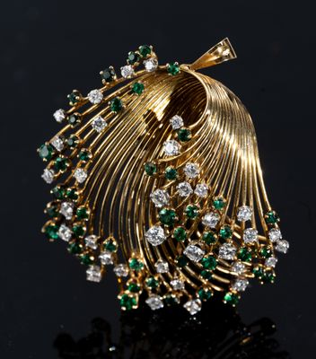 a close up of a gold broochle with green and white stones