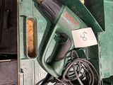 a green box with a corded drill and a corded cord in it