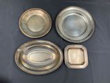 four silver plated trays on a table with a black background