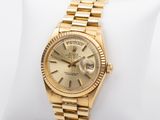 a close up of a gold rolex watch on a white pillow