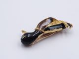a black and gold fish brooch on a white surface