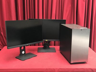 deux écrans d'ordinateur posés sur une table recouverte d'une nappe rouge