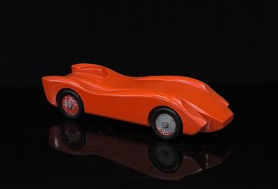 une petite voiture orange posée sur une surface noire