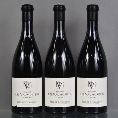 three bottles of red wine are lined up on a table