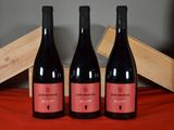 three bottles of red wine sit on a table next to a wooden box