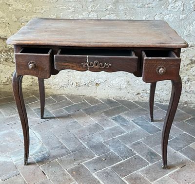 a small table with a drawer on it on a brick floor