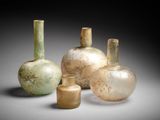 Plusieurs vases en verre sont posés sur une table devant un fond noir.