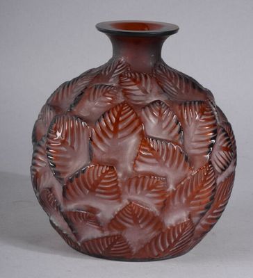 a brown vase with leaves on it on a white surface