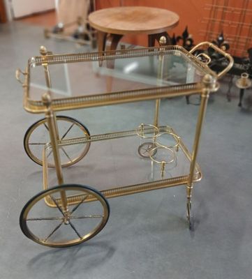 un chariot à boissons doré avec un plateau en verre, posé au sol
