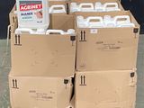 Plusieurs conteneurs remplis de liquide sont posés sur des palettes devant un mur noir