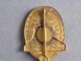 an image of a gold pin with a compass on top of it