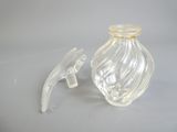 une bouteille en verre transparent avec un bouchon doré et un petit objet en plastique