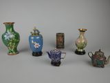 Plusieurs vases et théières sont alignés sur une surface grise