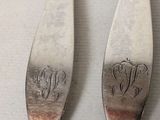 pair of silverware spoons with monograms on them on a table