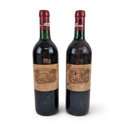 two bottles of red wine sitting next to each other on a white surface