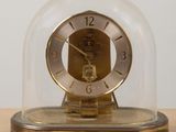 une horloge placée sous un dôme de verre sur une table