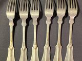 six forks are lined up in a row on a table