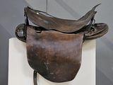 une selle de cheval exposée sur un socle blanc