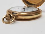 a gold pocket watch sitting on a white surface