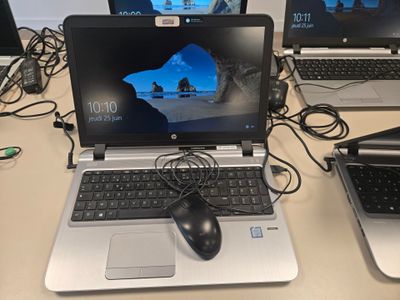 Trois ordinateurs portables sont posés sur une table, avec une souris et un clavier