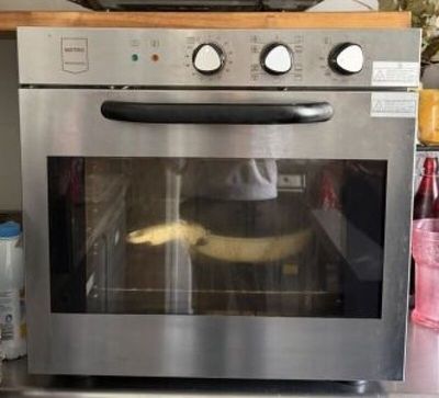 un four argenté avec une banane à l'intérieur, posé sur le plan de travail