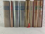 several old books are lined up on a white surface