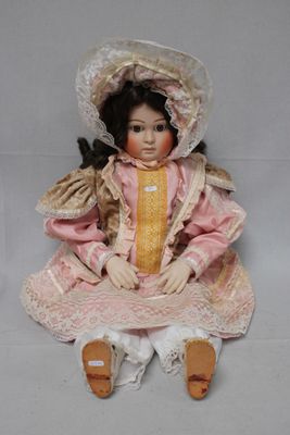 doll sitting on the floor wearing a pink dress and bonnet