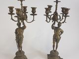 paire de candélabres anciens en laiton ornés de figurines sur leurs socles