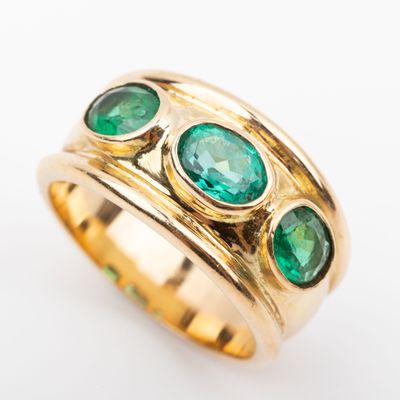 an image of a close up of a gold ring with green stones