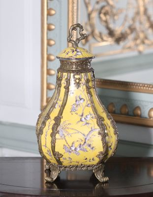 un vase jaune posé sur une table, avec un miroir en arrière-plan