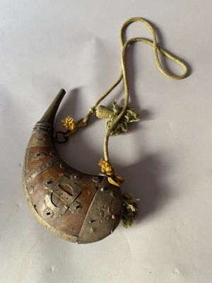 une image représentant un objet en laiton en forme de croissant suspendu à une corde