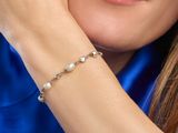close up of a woman wearing a blue shirt and a pearl bracelet