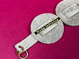 a keychain with a coin on it on a pink surface