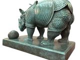 statue of a rhinocero with a ball on a marble base