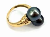 a close up of a black pearl ring on a white surface