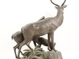 bronze sculpture of a stag and two young deer on a rock
