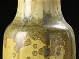 a yellow vase that has a lot of spots on it
