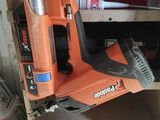 une agrafeuse sans fil orange posée sur une étagère en bois