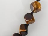 a close up of a tiger eye beaded necklace on a white surface
