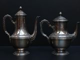 two silver teapots sitting on a black surface