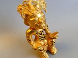 a gold figurine sitting on a white surface