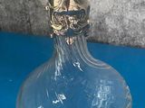 un vase en verre transparent avec un couvercle doré, posé sur une table bleue