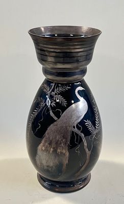 a black vase with a bird on it on a table