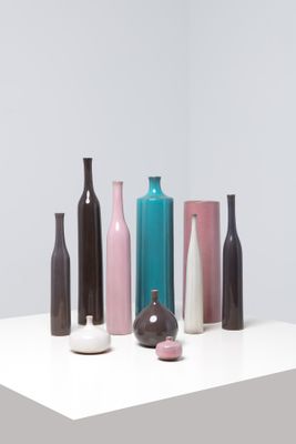 five different colored vases sitting on a white table