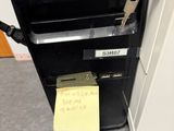 un ordinateur posé sur un bureau, avec un mot accroché dessus