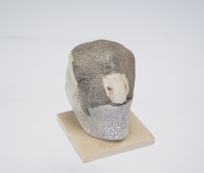 une petite sculpture représentant un homme barbu, posée sur un socle en bois
